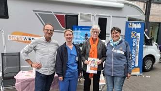 Drei Frauen und ein Mann vor einem Camper