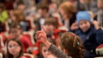 Kind meldet sich mit erhobenem Arm.