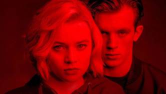 Junge Frau und junger Mann in rotes Licht getaucht.