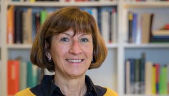 Portraitfotografie einer Frau mit einem verschwommenen Bücherregal im Hintergrund.