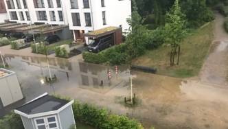Grundstückseinfahrten, Teile einer Straße und eines geflasterten Fussweges, die nach einen Starkregen unter Wasser stehen