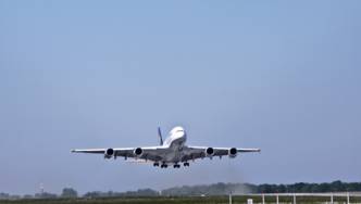 Ein großes Passagierflugzeug startet von einem Flughafen. Das Fahrwerk ist noch ausgefahren, es hebt gerade ab.