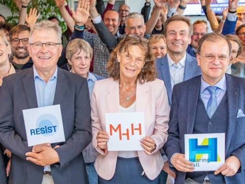 Group of people, three holding signs with logos in their hands
