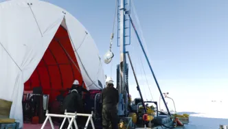 Wissenschaftler mit Sedimentbohrer in Eislandschaft.