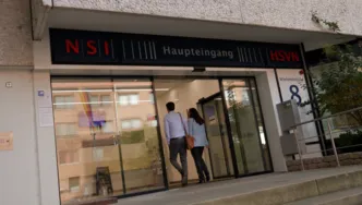Zwei Menschen gehen auf ein Glastür zu.